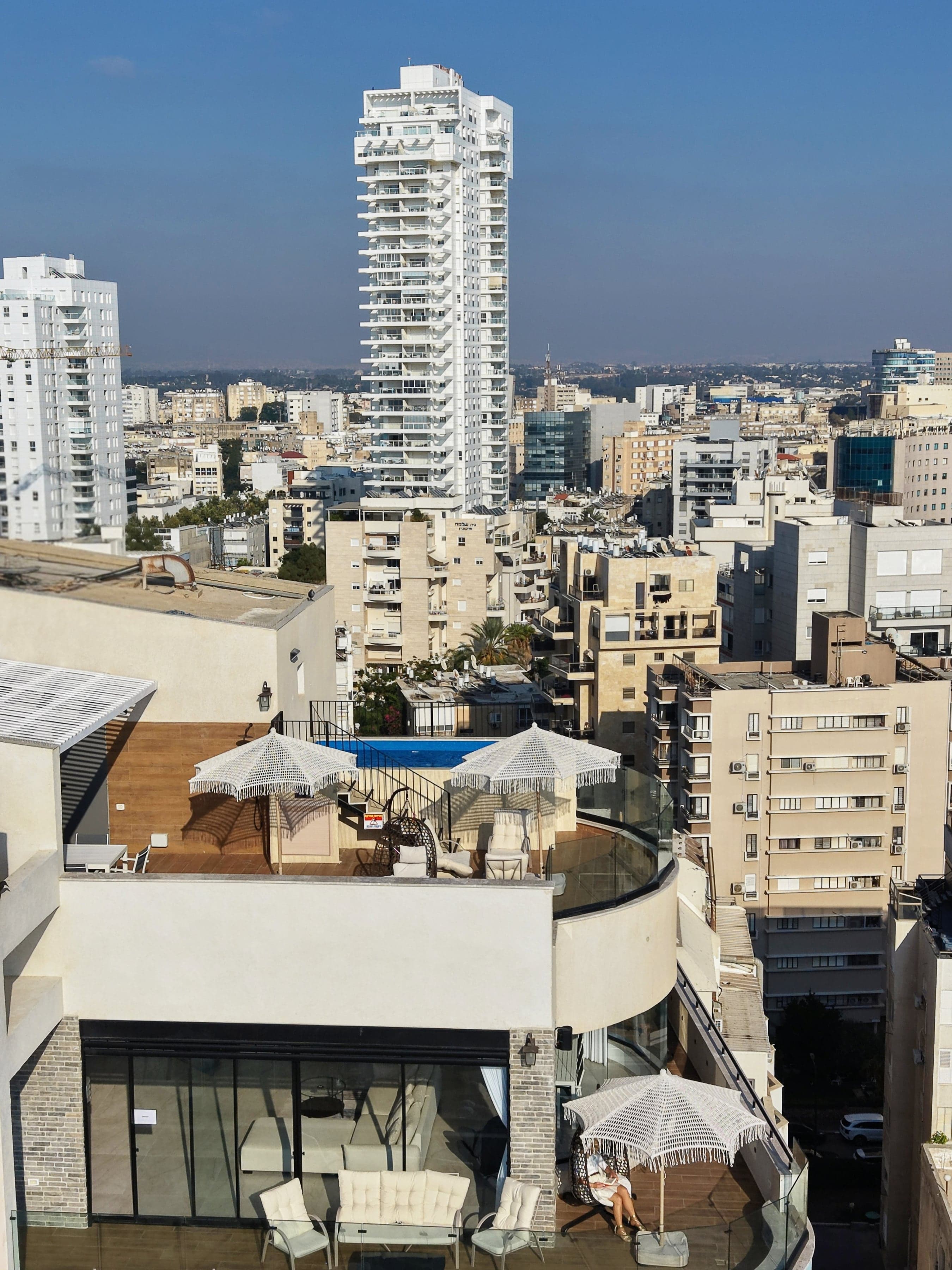 מרפסת הסלון של הגרנד פנטהאוז, ומעליה מרפסת הגג והבריכה, עם נוף לעיר
