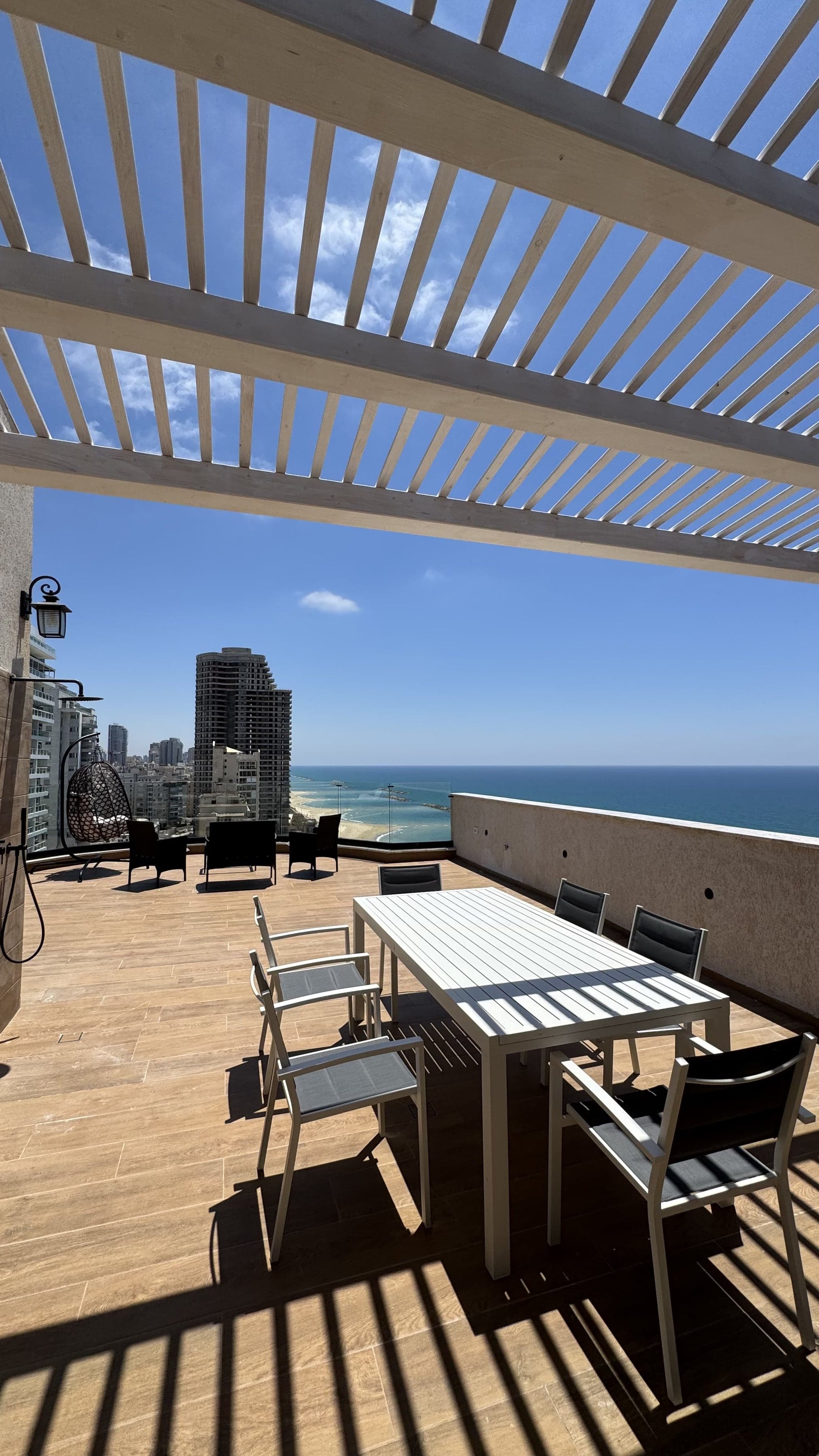 מרפסת הגג של המיני פנטהאוז עם פינת אוכל, מנגל ונוף לים
